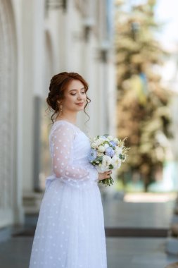 portrait of a young bride girl in a light dress walks in an urban environment
