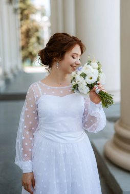 portrait of a young bride girl in a light dress walks in an urban environment