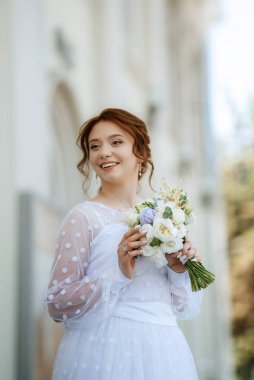 portrait of a young bride girl in a light dress walks in an urban environment
