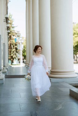 portrait of a young bride girl in a light dress walks in an urban environment