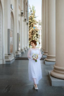 portrait of a young bride girl in a light dress walks in an urban environment