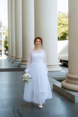portrait of a young bride girl in a light dress walks in an urban environment