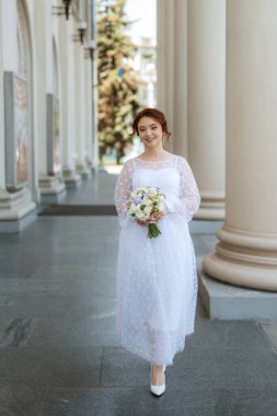 portrait of a young bride girl in a light dress walks in an urban environment