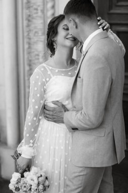 bride in a light wedding dress with a bouquet next to the groom in a blue suit