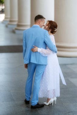 bride in a light wedding dress with a bouquet next to the groom in a blue suit