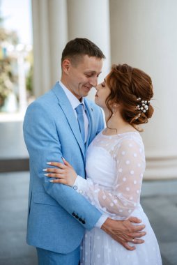 bride in a light wedding dress with a bouquet next to the groom in a blue suit