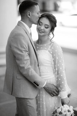 bride in a light wedding dress with a bouquet next to the groom in a blue suit