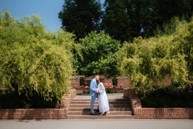 bride in a light wedding dress with a bouquet next to the groom in a blue suit