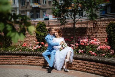 bride in a light wedding dress with a bouquet next to the groom in a blue suit