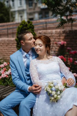 bride in a light wedding dress with a bouquet next to the groom in a blue suit
