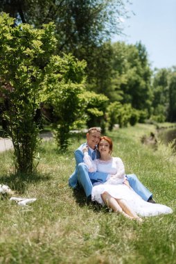 bride in a light wedding dress with a bouquet next to the groom in a blue suit