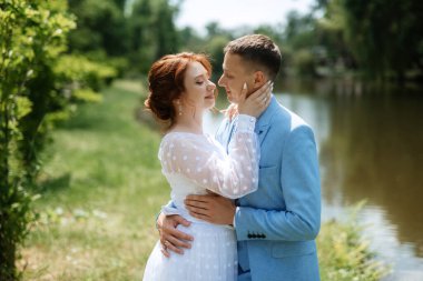 bride in a light wedding dress with a bouquet next to the groom in a blue suit