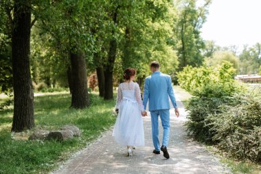 bride in a light wedding dress with a bouquet next to the groom in a blue suit