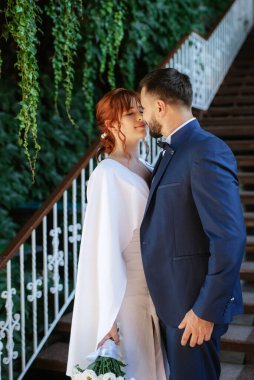 bride in a white dress with a bouquet and the groom in a blue suit on their wedding day