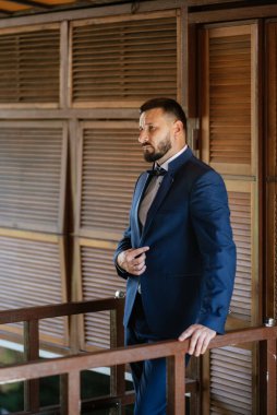 portrait of a groom with a beard in a blue suit and bow tie