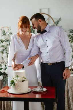 newlyweds happily cut, laugh and taste the wedding cake