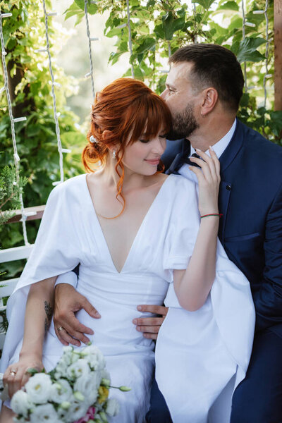 bride in a white dress with a bouquet and the groom in a blue suit on their wedding day