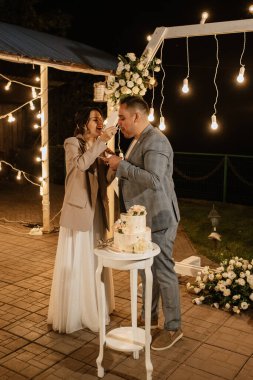 newlyweds happily cut, laugh and taste the wedding cake