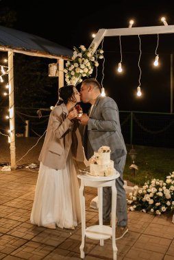 newlyweds happily cut, laugh and taste the wedding cake