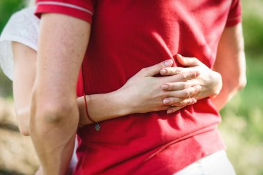 couple in love a blonde girl and a guy in a red t-shirt at a picnic in a park with green grass