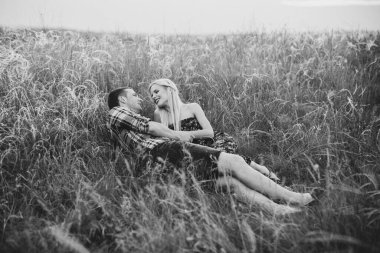 couple in love blonde girl and guy in the grass at sunset
