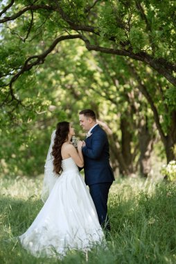 the groom and the bride are walking in the forest on a bright day