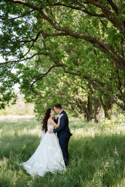 the groom and the bride are walking in the forest on a bright day