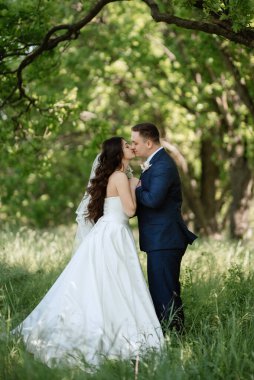 the groom and the bride are walking in the forest on a bright day