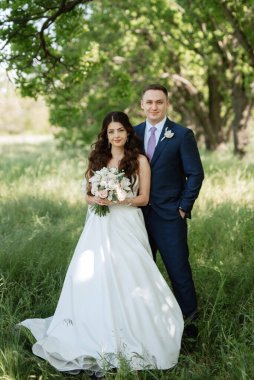 the groom and the bride are walking in the forest on a bright day