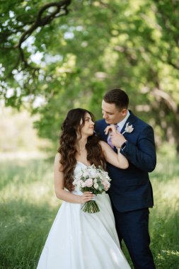 the groom and the bride are walking in the forest on a bright day