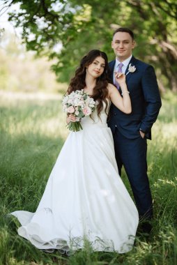 the groom and the bride are walking in the forest on a bright day