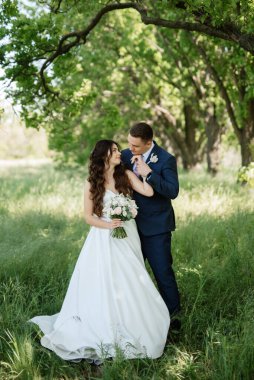 the groom and the bride are walking in the forest on a bright day
