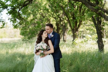 the groom and the bride are walking in the forest on a bright day