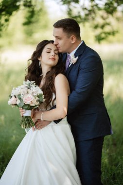 the groom and the bride are walking in the forest on a bright day