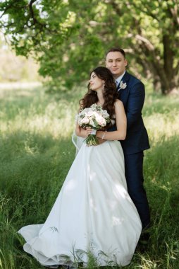 the groom and the bride are walking in the forest on a bright day