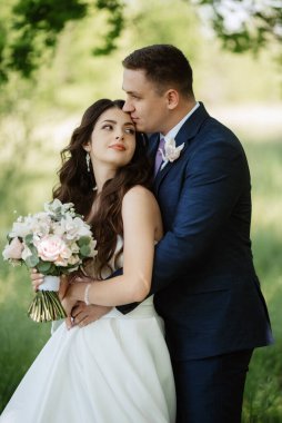 the groom and the bride are walking in the forest on a bright day