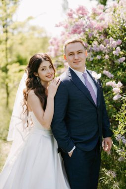 the groom and the bride are walking in the forest on a bright day
