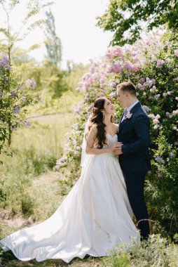 the groom and the bride are walking in the forest on a bright day