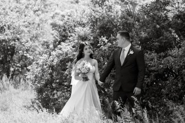 the groom and the bride are walking in the forest on a bright day