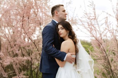the groom and the bride are walking in the forest on a bright day