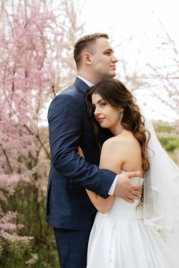 the groom and the bride are walking in the forest on a bright day