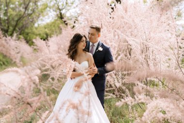 the groom and the bride are walking in the forest on a bright day
