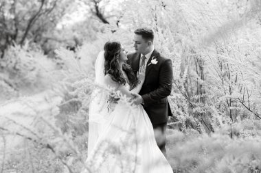 the groom and the bride are walking in the forest on a bright day