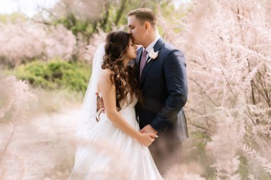 the groom and the bride are walking in the forest on a bright day