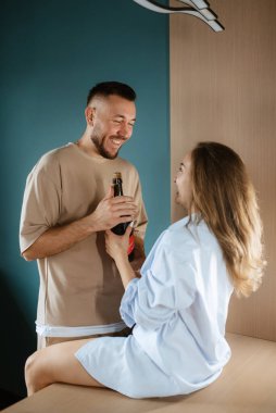 earlier morning the bride and groom at home in the kitchen drinking champagne