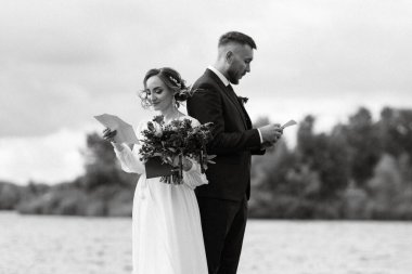 the first meeting of the bride and groom in wedding dresses on the pier near the water