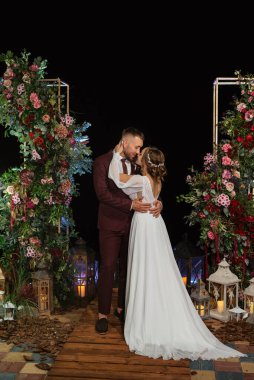 newlyweds in the evening on the wedding arch on the pier after the ceremony