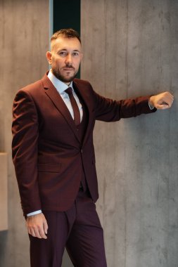 portrait of smiling groom with beard in marsala color suit