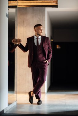 portrait of smiling groom with beard in marsala color suit
