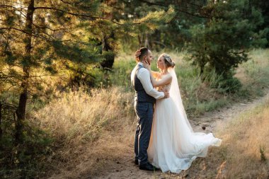 the groom and the bride are walking in the forest on a bright day